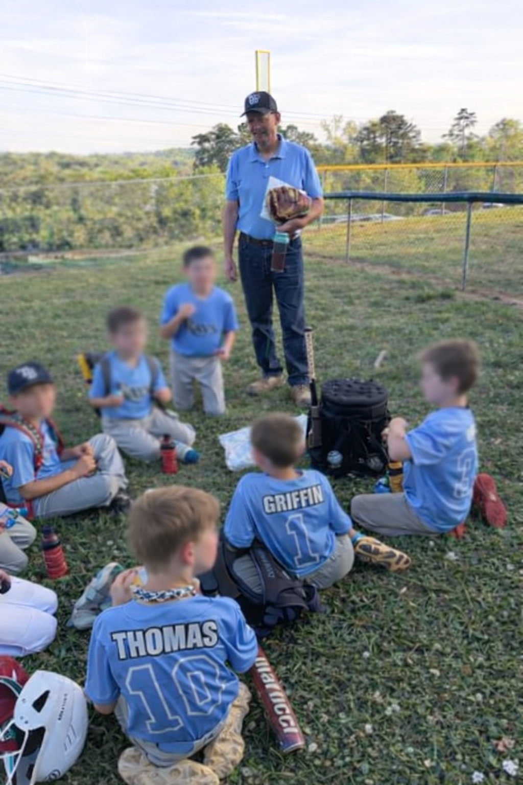 Greg coaching a youth baseball team during a huddle